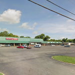 Suburban strip mall with Family Dollar, parking lot, and nearby trees on a sunny day.