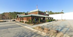 Texas Roadhouse restaurant with green metal roof and parking lot in Hiram, GA.