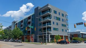 Modern Lakeview Green apartment building at city intersection with balconies and commercial spaces.