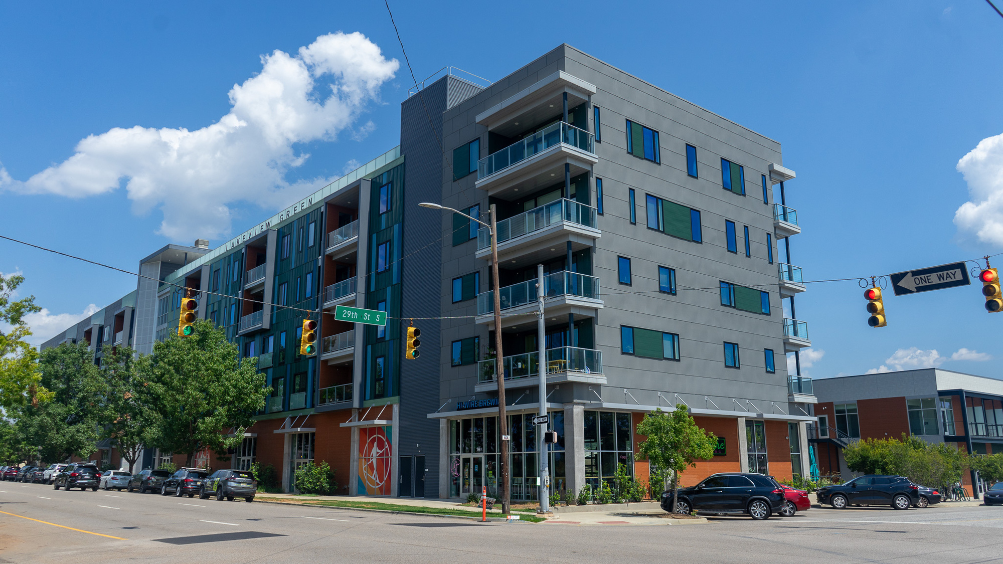 Modern Lakeview Green apartment building at city intersection with balconies and commercial spaces.